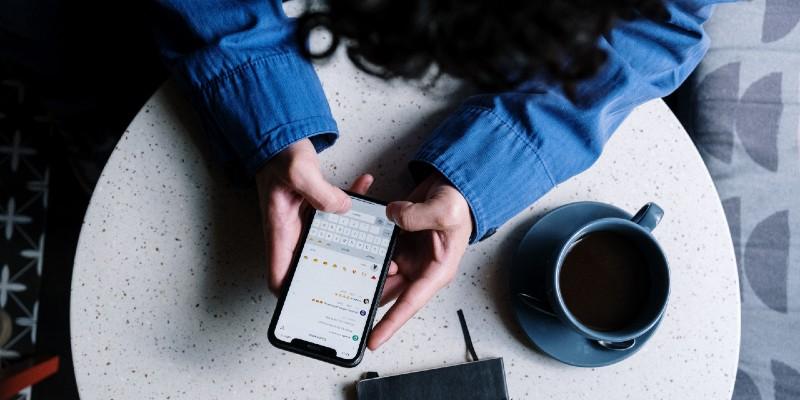 Ηθοποιός χρησιμοποιεί τα social media από το κινητό της καθισμένη σε τραπέζι με καφέ και σημειωματάριο