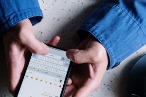 Ηθοποιός χρησιμοποιεί τα social media από το κινητό της καθισμένη σε τραπέζι με καφέ και σημειωματάριο