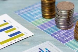 Γυαλιά οράσεως, νομίσματα, στιλό, κομπιουτεράκι και κάρτες με γραφήματα και πίνακες επάνω σε τραπέζι